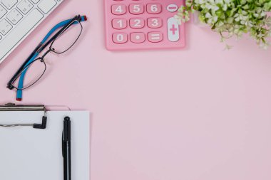 Pastel pembe ofis masası klasör, klavye, kalem, gözlük ve hesap makinesi. Kopyalama alanı olan üst görünüm. Çalışma masası konsepti.
