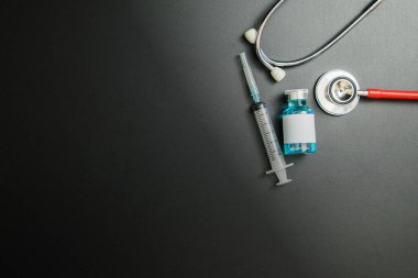 Doctor 's Day ve Covid-19 konsepti. Mavi ilaç şişesi, iğne ve steteskop.