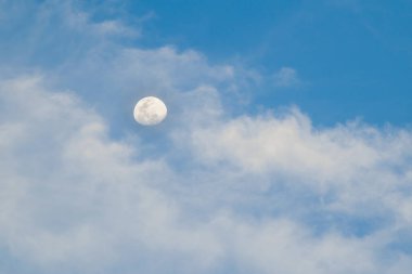 Bulutlu parlak mavi gökyüzü ve gündüz vakti ay.