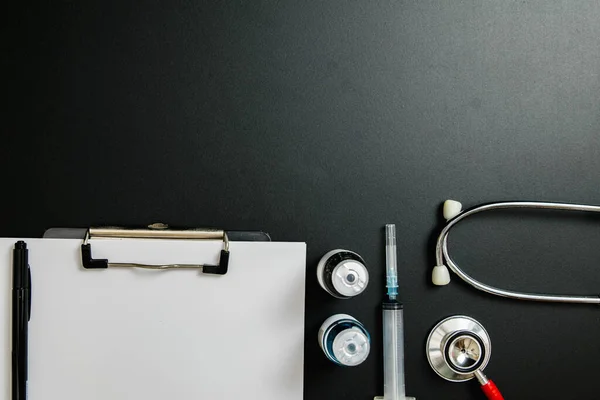 Doctor 's Day ve Covid-19 konsepti. Üzerinde mavi beyaz ilaç şişesi, iğne ve steteskop olan klip tahtası.