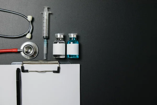 Doctor 's Day ve Covid-19 konsepti. Üzerinde mavi beyaz ilaç şişesi, iğne ve steteskop olan klip tahtası.