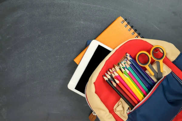 Okul konseptine geri dönelim. Sırt çantasında okul malzemeleri, tablet ve tebeşir tahtası var. Üst Manzara. Boşluğu kopyala