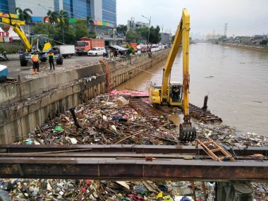Büyük bir nehirdeki çöpleri temizleyen kazıcılar. yağmur derlemesi geliyor