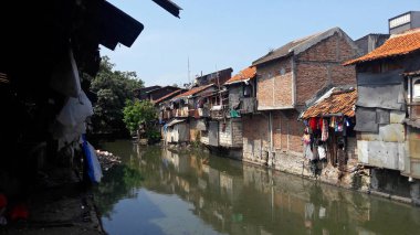 Batı Cakarta, Endonezya - 28 Ekim 2018 Kirli bir nehrin kıyısındaki gecekondu bölgesi