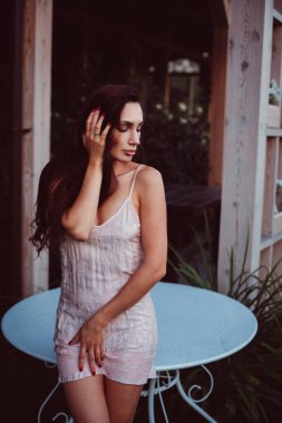 Genç ve güzel bir kız, parlak dudakları ve uzun siyah saçları var. Gömlek giyip gecenin geç saatlerinde bahçede dolaşıyor.