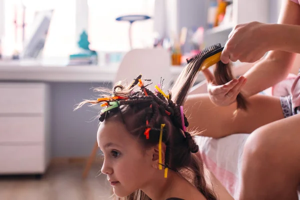 Mom made her daughter a hairstyle, a lot of curls, daughter is happy and plays with curls