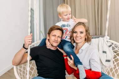 Mutlu bir aile, anne, baba ve küçük oğlu aydınlık bir odada, gülüyorlar, sarılıyorlar, anne ve babaya sarılıyorlar.