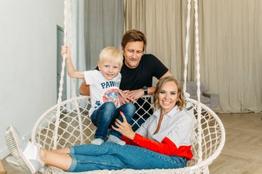 Mutlu bir aile, anne, baba ve küçük oğlu aydınlık bir odada, gülüyorlar, sarılıyorlar, anne ve babaya sarılıyorlar.