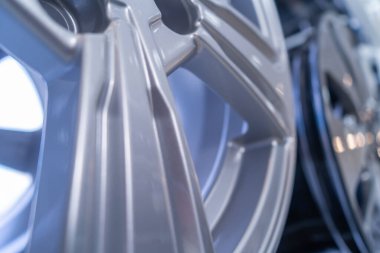 Araba alaşımlı tekerlekler, metalik renkte, bir standın üzerinde sıralanmış, kapalı alanda ateş eden, yanıp sönen ışıklar.