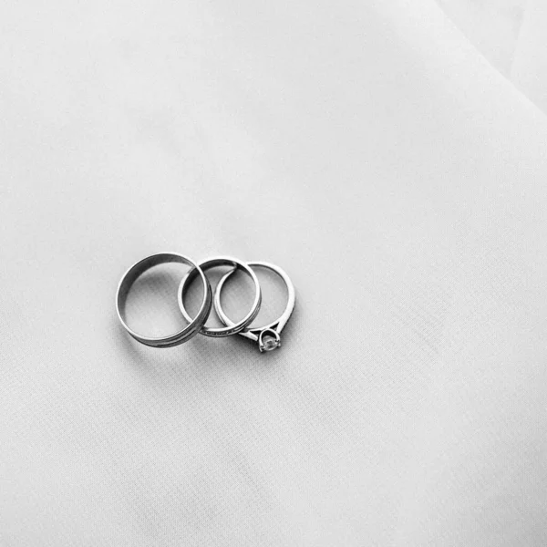 結婚指輪と結婚指輪は白い布の横にあり 窓からの光 — ストック写真