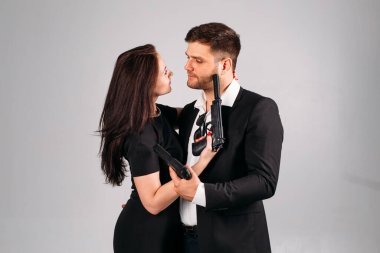 Genç bir kız ve siyah takım elbiseli ellerinde kollarıyla stüdyoda beyaz bir arka planda korumaları ya da ajanları resmediyorlar.