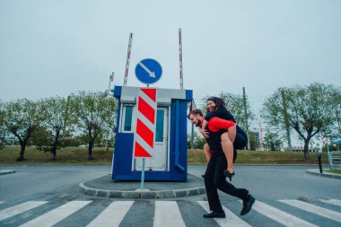 Kırmızı elbiseli genç bir kız ve kırmızı elbiseli bir adam cadde boyunca yürür ve kırmızı ve mavi nesnelerin arka planlarıyla fotoğraf çekerler.