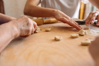 Aile gelenekleri masada, torun ve anne büyükbabaya mantı yapmalarında yardım ediyor, aile birlikte mutlu, iletişim kuruyorlar ve eğleniyorlar.
