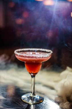 Bardakta parlak içkiler, arka planda ışık ve duman. Farklı renkte kokteyller