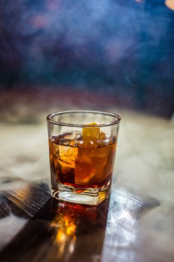 Bardakta parlak içkiler, arka planda ışık ve duman. Farklı renkte kokteyller