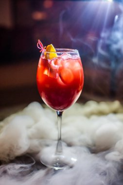 Bardakta parlak içkiler, arka planda ışık ve duman. Farklı renkte kokteyller