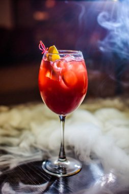 Bardakta parlak içkiler, arka planda ışık ve duman. Farklı renkte kokteyller