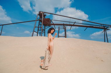 Bikinili güzel kıvırcık kız ve kumlu bir sahilde çıplak, kum ve gökyüzü.