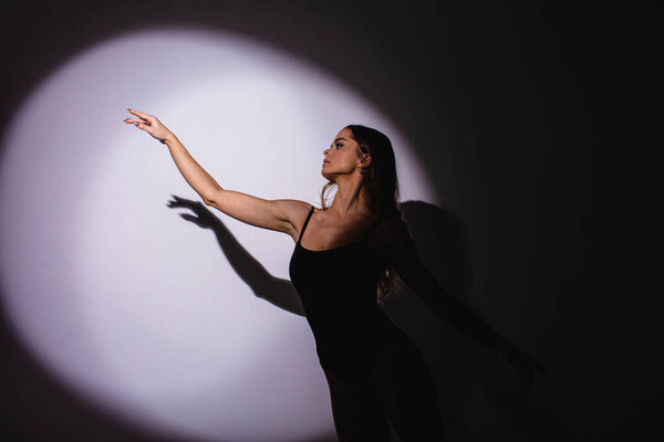 Girl dancer, flexible plastic, dancing in a jump. spotlight, hand shadow.