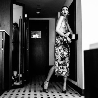 Genç, güzel, uzun boylu, yarı çıplak bir manken soyunma odasında farklı kıyafetler deniyor.