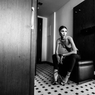 Genç, güzel, uzun boylu, yarı çıplak bir manken soyunma odasında farklı kıyafetler deniyor.