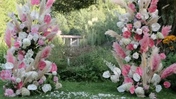 美丽的拱门在阳光下从淡淡的粉红黄色的草地和玫瑰衬托下 在一个小喷泉的背景下 水从那里流出 房子的背景反映在水里 — 图库视频影像