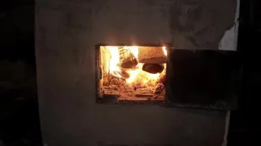 Kulübede, köyde, sarı bir ateş fırındaki odundan yanıyor. Kapı açık, yakın plan, çok sıcak.