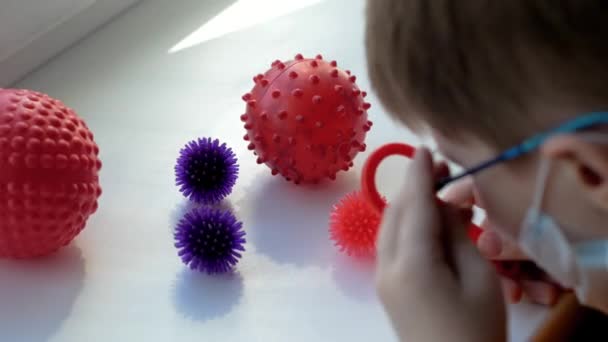 Evin Penceresindeki Bir Çocuk Tıbbi Maske Gözlüklerle Oyuncak Bir Büyüteçle — Stok video