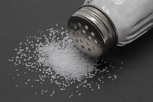 Verschüttetes Salz auf schwarzem Hintergrund — Stockfoto