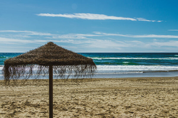 Straw umbrellas on empty beach in Marbella, Spain. early morning.