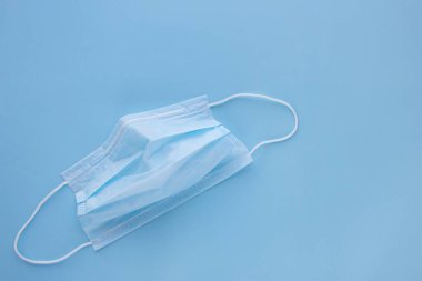 Mavi arka planda lastik kulaklıklı tıbbi maske kullanılmış. Virüs ve bakteri kavramından koru