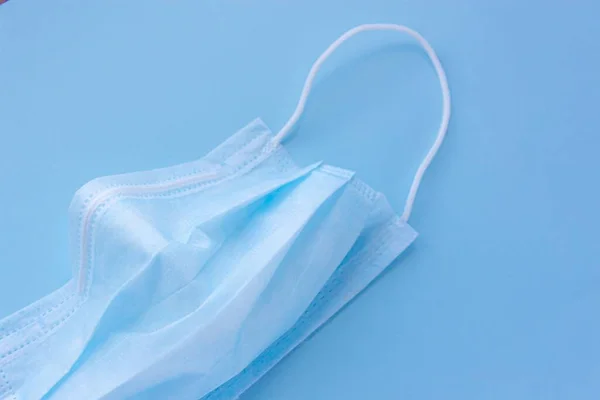  Mavi arka planda lastik kulaklıklı tıbbi maske kullanılmış. Virüs ve bakteri kavramından koru