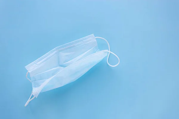  Mavi arka planda lastik kulaklıklı tıbbi maske kullanılmış. Virüs ve bakteri kavramından koru
