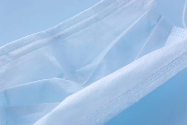 Mavi arka planda plastik kulaklıkla kullanılmış ilaç maskesini kapatın. Virüs ve bakteri kavramından koru