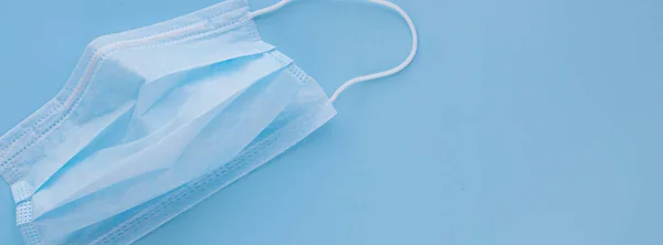  Mavi arka planda lastik kulaklıklı tıbbi maske kullanılmış. Virüs ve bakterilerden koru. Sancak konsepti