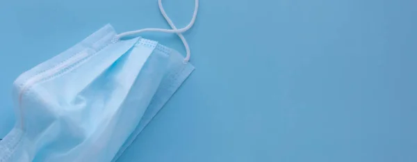  Mavi arka planda lastik kulaklıklı tıbbi maske kullanılmış. Virüs ve bakterilerden koru. Sancak konsepti