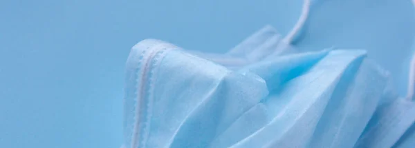  Mavi arka planda lastik kulaklıklı tıbbi maske kullanılmış. Virüs ve bakterilerden koru. Sancak konsepti