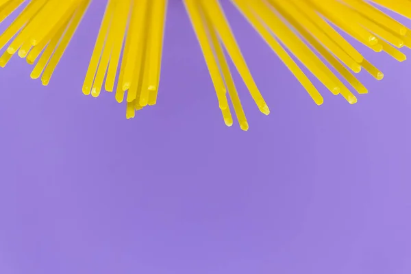 Lange gele spaghetti pasta op violette achtergrond. Gele Italiaanse pasta. Italiaans eten en keuken concept. kopieerruimte — Stockfoto