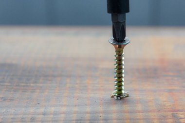 Metal vida ahşap tahta yüzeye tornavidayla tutturulmuş. ev ya da atölye onarım kavramı