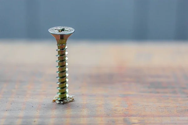 El tornillo de metal tripulado en la superficie del tablero de madera con destornillador. concepto de reparación del hogar o taller —  Fotos de Stock