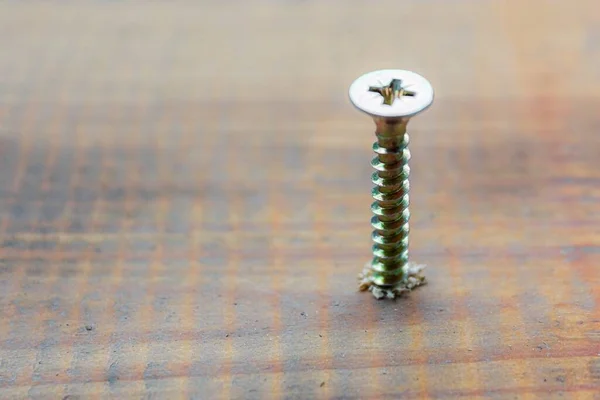 El tornillo de metal tripulado en la superficie del tablero de madera con destornillador. concepto de reparación del hogar o taller —  Fotos de Stock