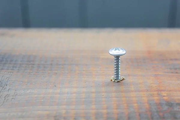 El tornillo de metal tripulado en la superficie del tablero de madera con destornillador. concepto de reparación del hogar o taller —  Fotos de Stock