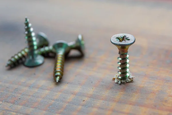 Die Metallschraube, die mit einem Schraubenzieher in die Holzbrettoberfläche eingedrückt wird. Reparaturkonzept zu Hause oder in der Werkstatt — Stockfoto