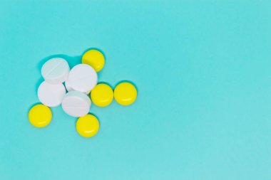 Mavi arka planda beyaz ve sarı yuvarlak haplar. Yakın plan planı. tıbbi tedavi kopyalama alanı kavramı 