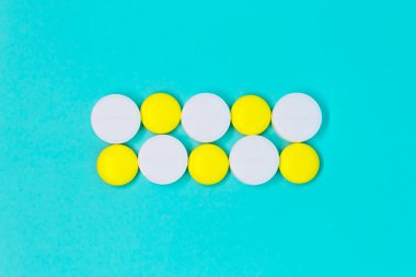 Beyaz ve sarı yuvarlak haplar mavi arka plan yakın plan planında. tıbbi tedavi kopyalama alanı kavramı 