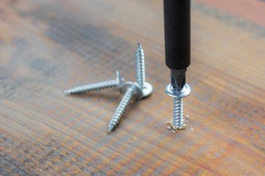 Beyaz metal vida, siyah tahta tahta yüzeye yakın çekim tornavidayla vidalanmış. ev ya da atölye onarım kavramı