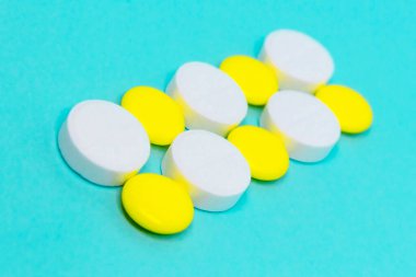 Beyaz ve sarı yuvarlak haplar mavi arka plan yakın plan planında. tıbbi tedavi kopyalama alanı kavramı 