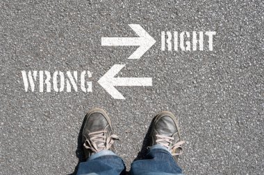 Doğru ve yanlış yazıtlarla asfalt üzerinde duran kişinin kırpılmış görüntüsü