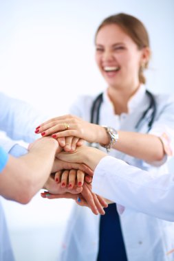 Doktorlar ve hemşireler tıbbi bir ekipte el ele tutuşuyorlar.