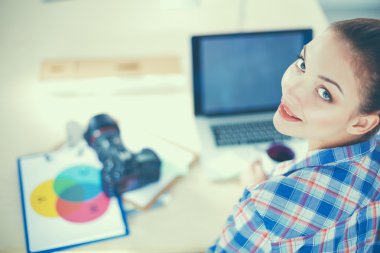 Masada dizüstü bilgisayarla oturan kadın fotoğrafçı.